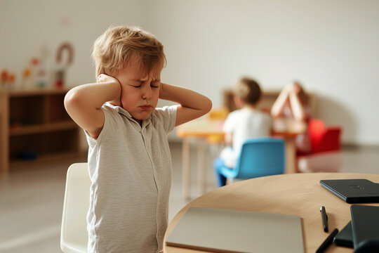 Child covering ears in classroom—illustration of sensory sensitivity and social challenges in autism.