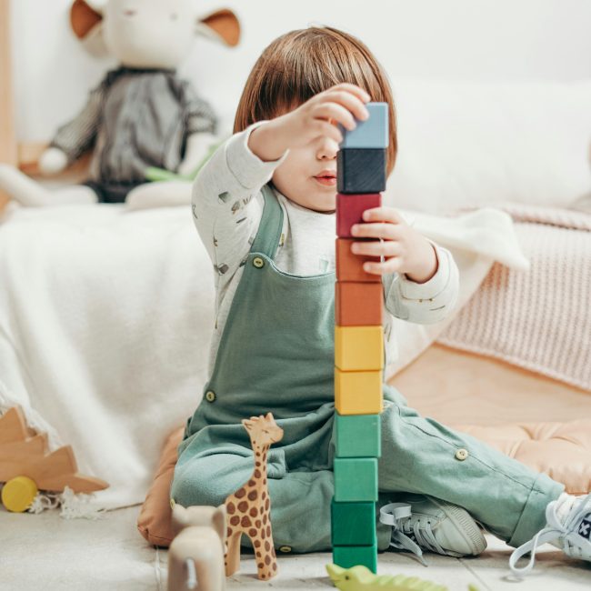 Child playing with wooden blocks in cozy room—symbolic of creativity, early childhood learning, and developmental play.